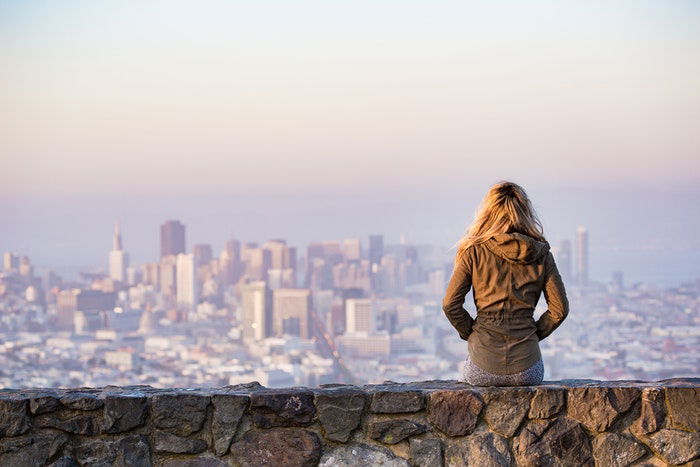 Girl sitting and looking out at urban scene 