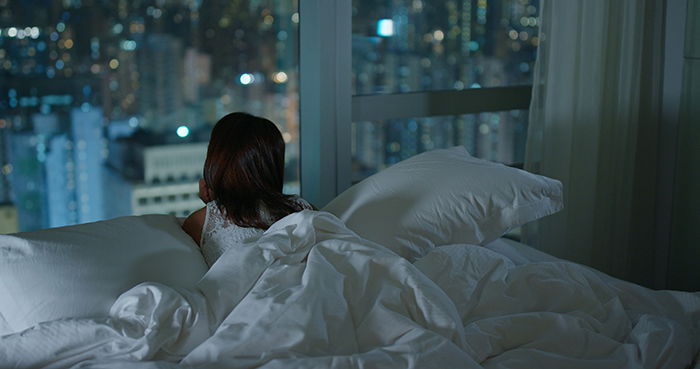 Mujer mirando la ciudad desde la ventana por la noche.