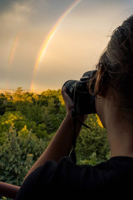 A person photographing a rainbow