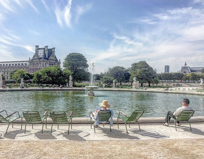 photo of a fountain with green chairs around