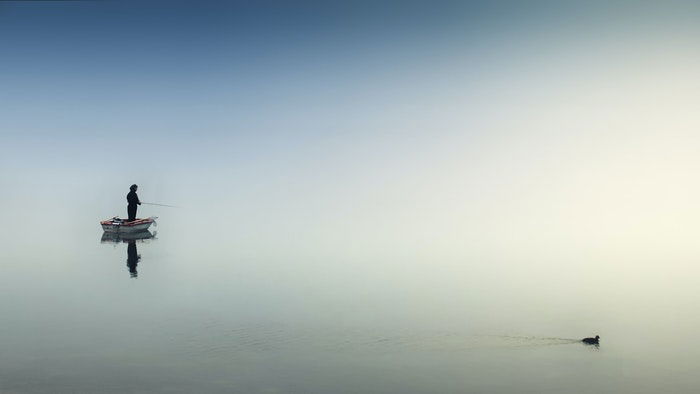 photo of a fisherman on a boat on a lake