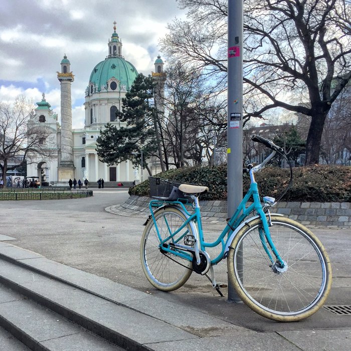 photo of a turquoise bike with a church in the background