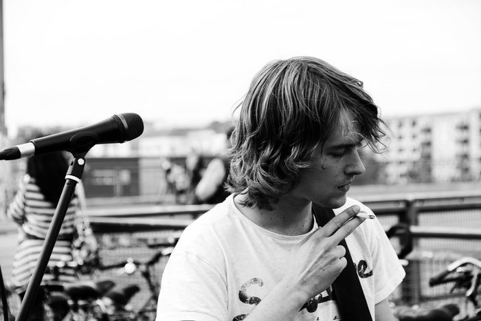 Black and white portrait of a musician smoking a cigarette onstage