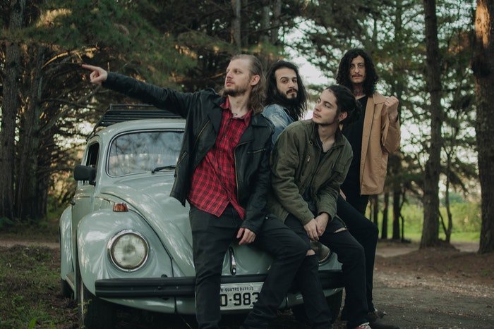 A music band posing by an old car