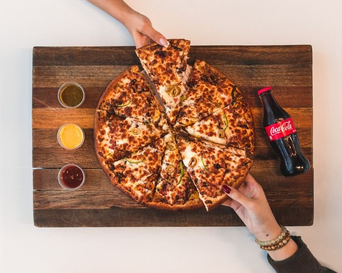 overhead photo of hands taking slices of pizza