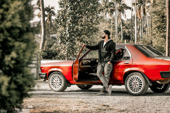 Photo of a man standing next to a red sports car