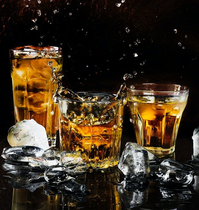 Three whiskey cocktails surrounded by ice
