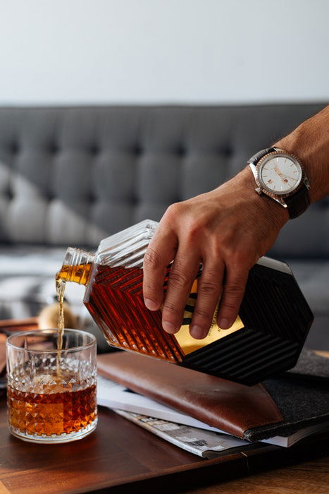 A person pouring whiskey into a glass