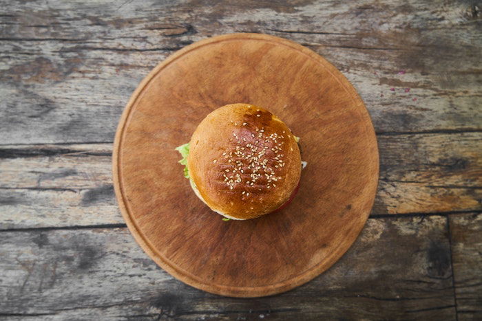 Flat lay food photo of a hamburger on a wooden plate