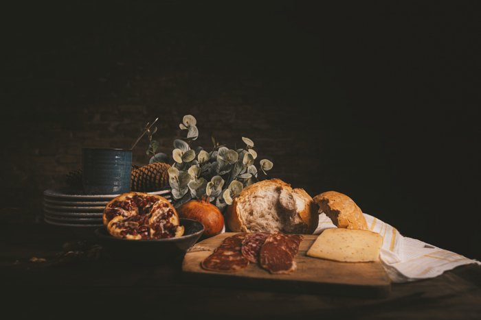 Still life photo with brad, ham, cheese and plates on a table