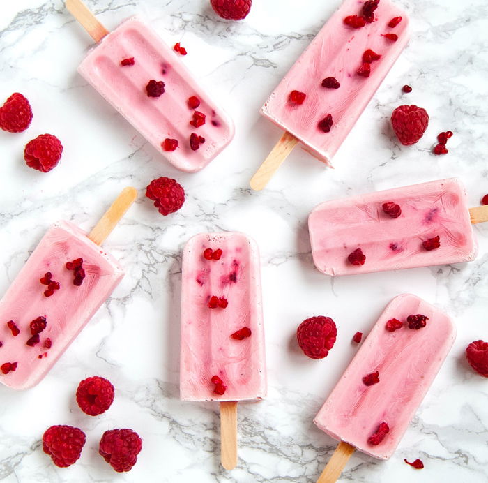 Flat lay photo of fruity ice lollys and raspberries