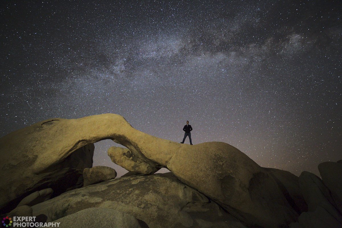 An environmental starry-night sky portrait with an ExpertPhotography graphic watermark