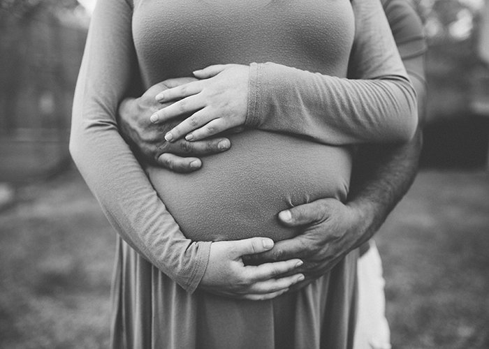 Black and white maternity photography with crossing hands.