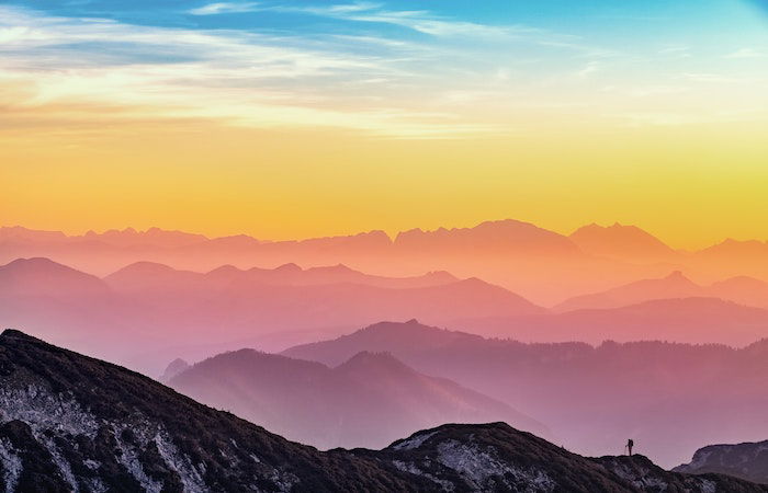 Colorful landscape oof sky and mountains with a hiker