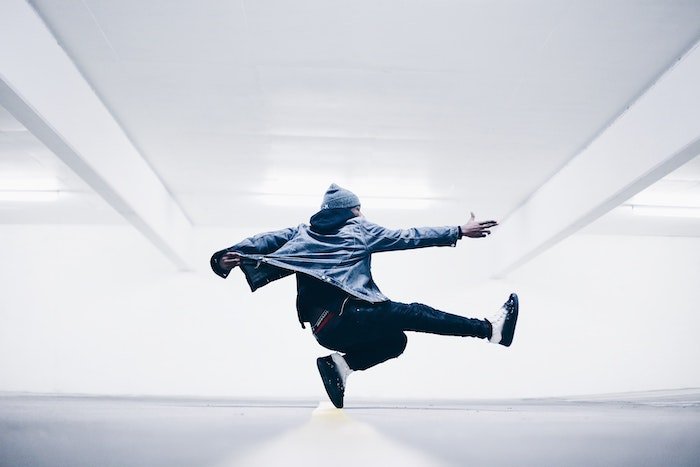 A urban breakdancer posing in a large white room