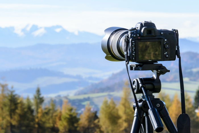 A DSLR on a tripod in front of a stunning landscape