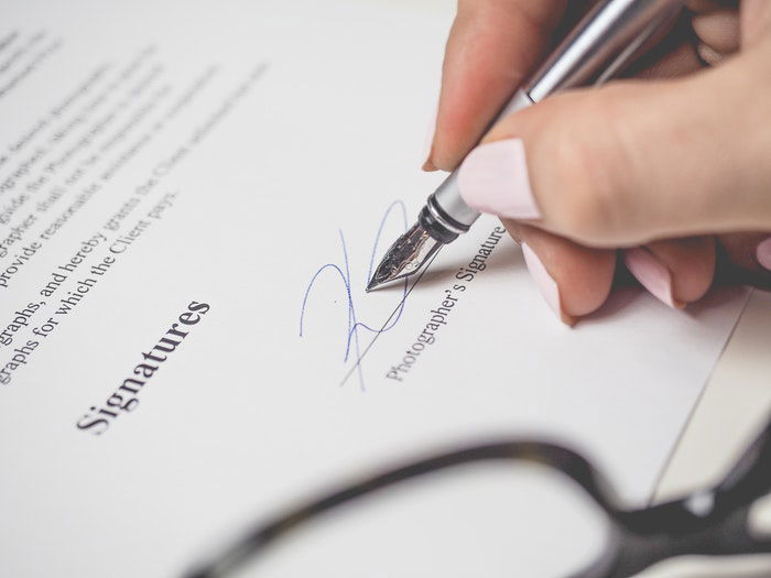 A close up of a person signing a stock photography contract