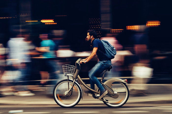 A man riding a bike past a busy marketplace