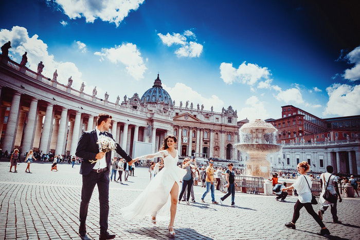 A wedding portrait of the newlyweds walking hand in hand in an outdoor plaza