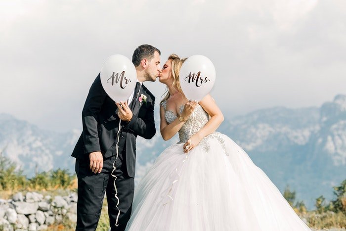Newlywed couple kissing outdoors and holding 'Mr & Mrs' Balloons