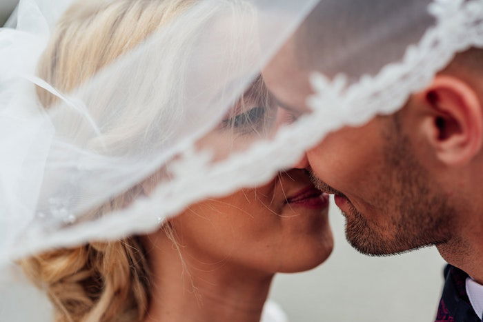 A wedding portrait closeup of the newlyweds kissing outdoors