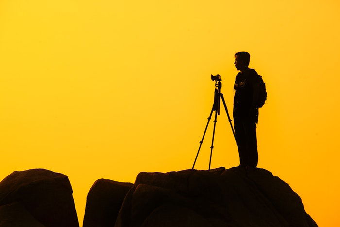 A wildlife photographer silhouetted against the sunset