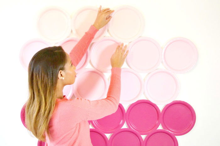 A person hanging pink plates as a DiY photography background