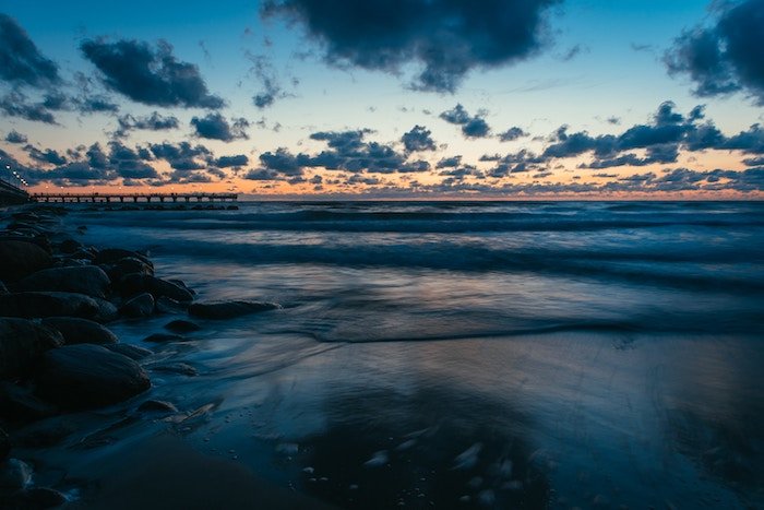 A one second exposure of a sea shore at dusk with clouds in the sky