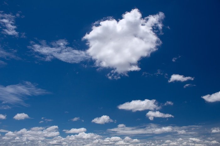 A white cloud against a blue sky with other clouds in the distance