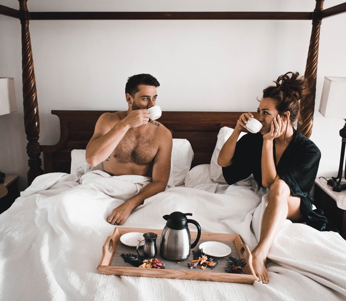 A couple drinking coffee in bed together