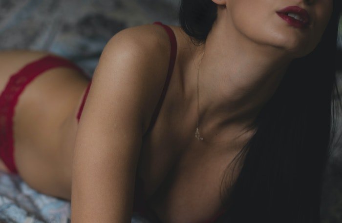 Beautiful close up DIY boudoir photo of a girl in red lingerie posing on a bed