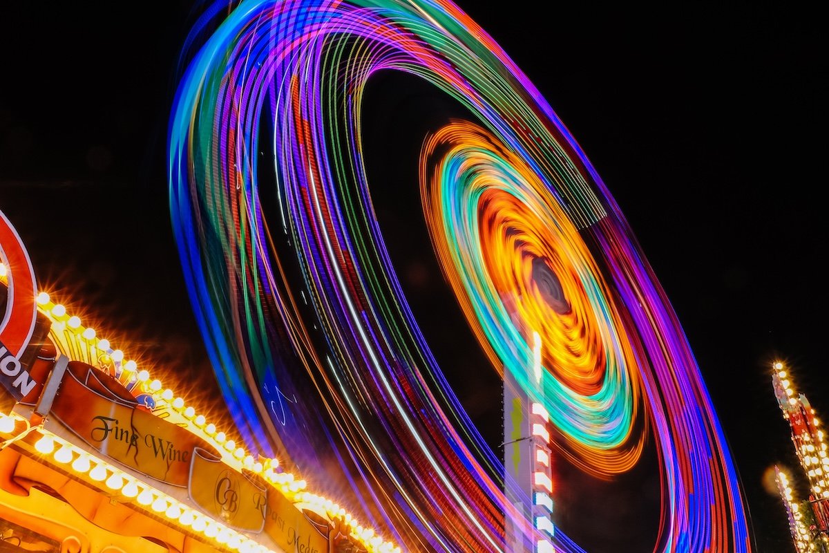 A long-exposure night photography shot of an amusement park ferris wheel with colorful motion lines shot with a slow shutter speed