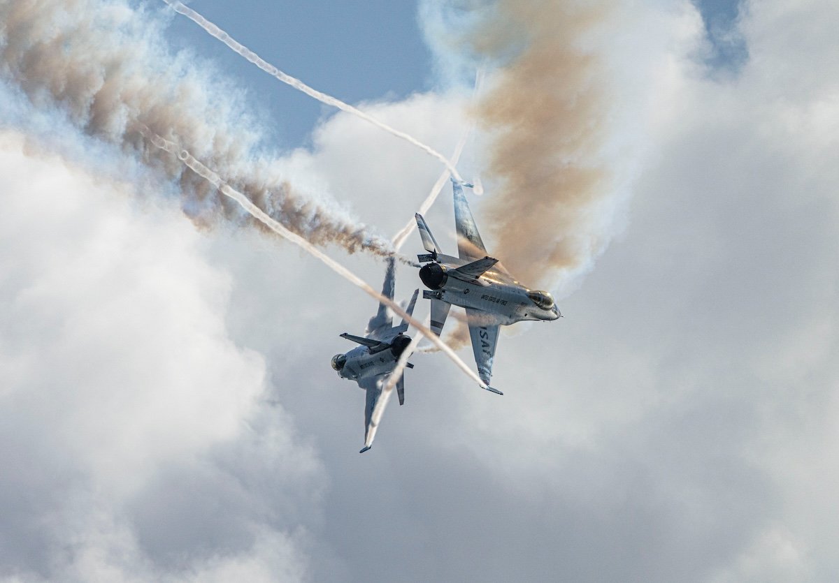 Fighter planes flying in the sky crossing paths with smoke billowing behind them