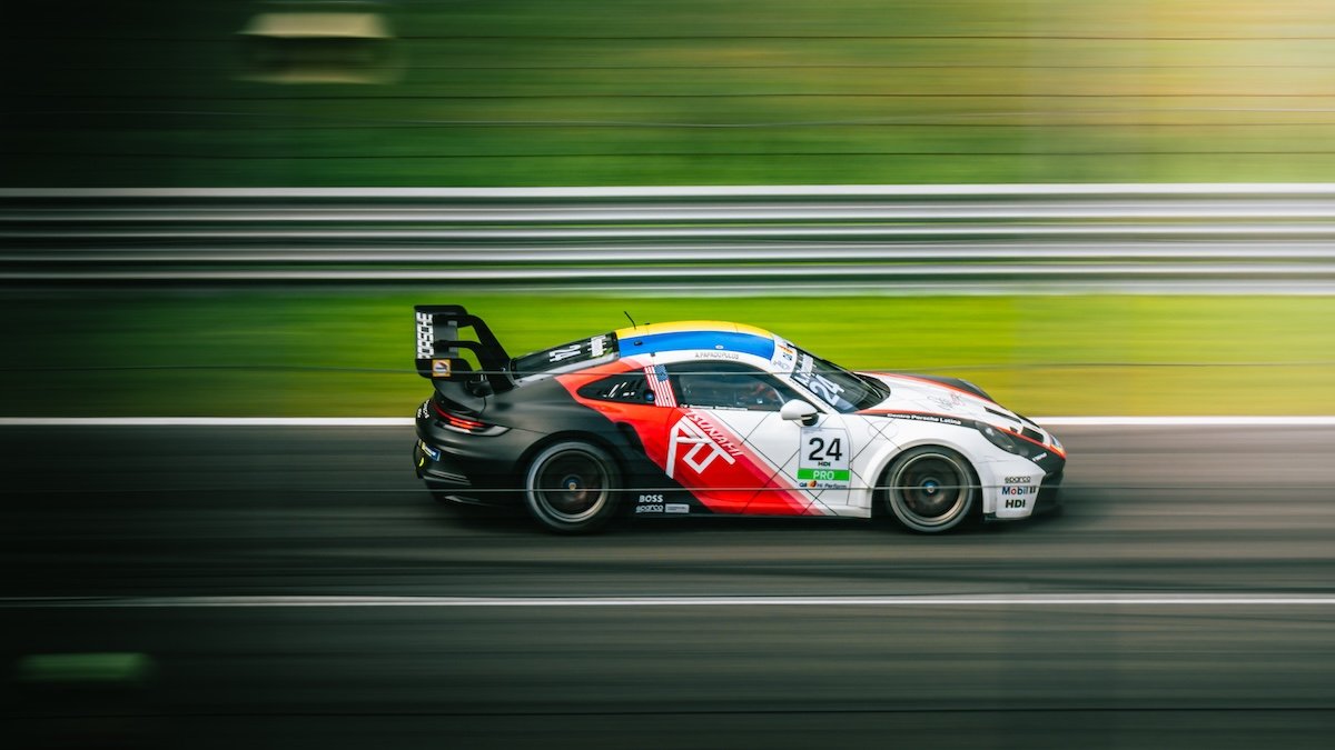 A porsche race car going fast on a face course with a blurred background