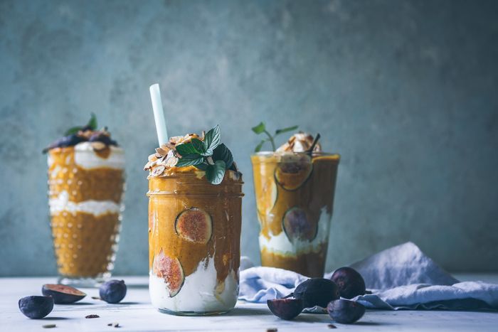 photo of smoothies in different glasses in front of a neutral background