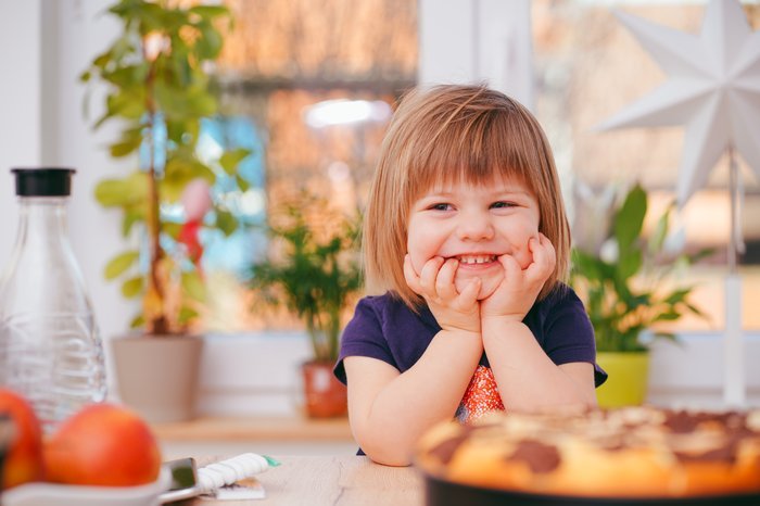 Cute lifestyle portrait of a little girl at a kitchen table