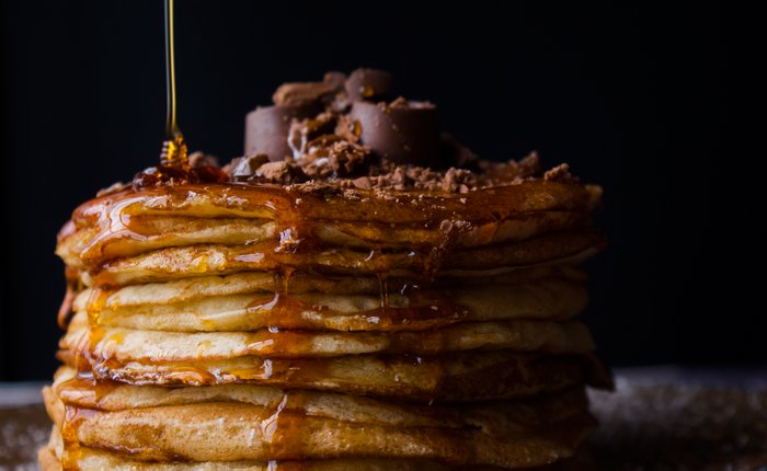 Pouring syrup on a stack of pancakes