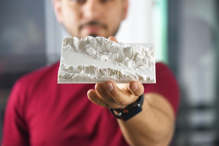 a photo of a nan holding a landscape 3d print 