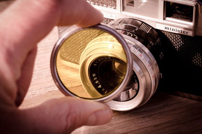 A hand holding a camera filter to a Minister camera