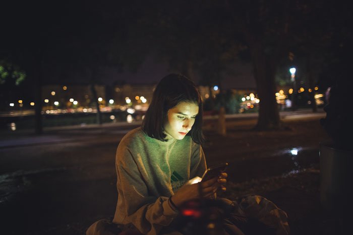 A girl using a smartphone on a city rooftop at night
