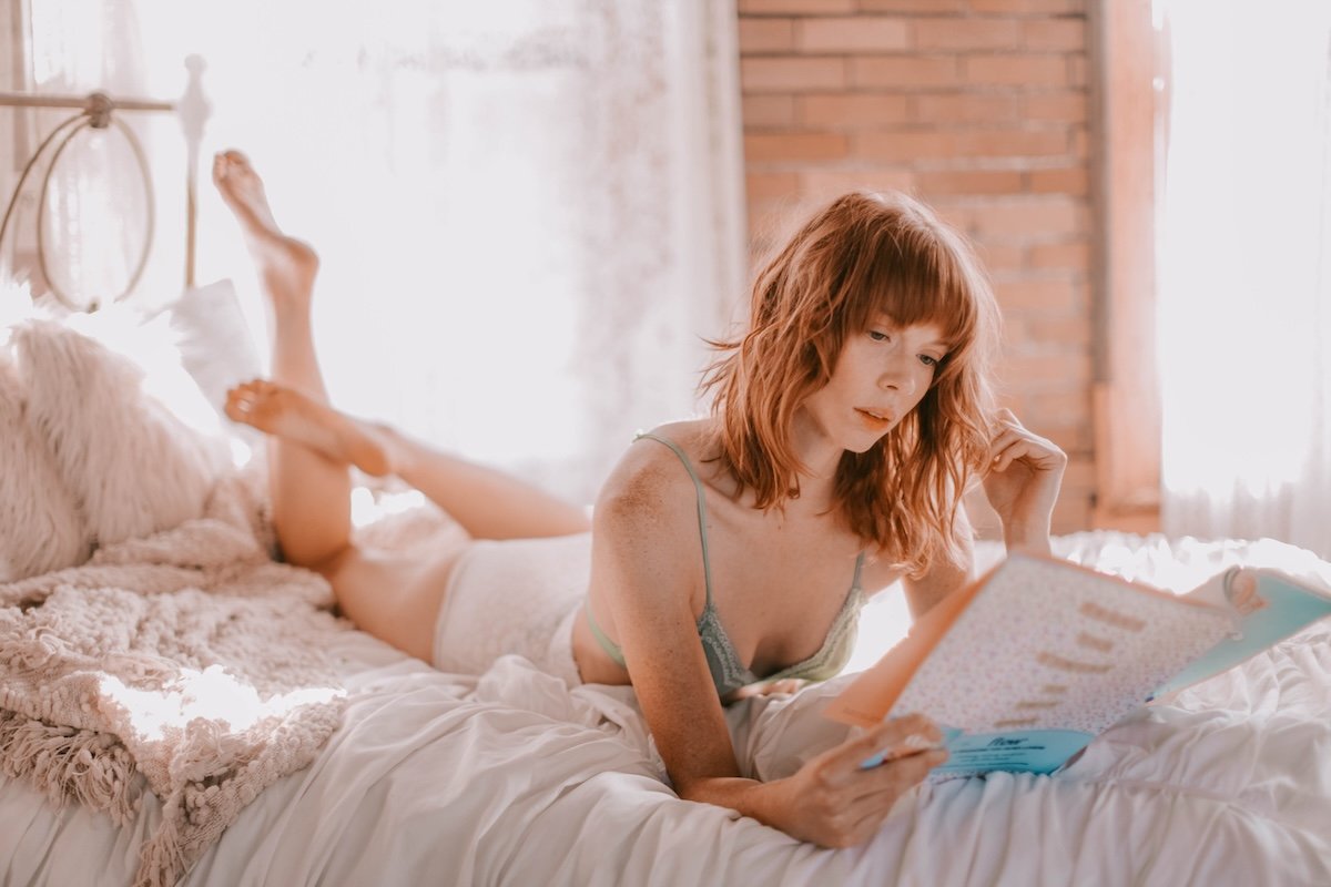 A woman reading a magazine in bed as an example for casual DIY boudoir photos