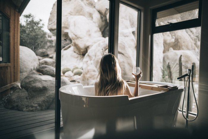 photo of a woman sitting in a bathtub holding a glass of wine