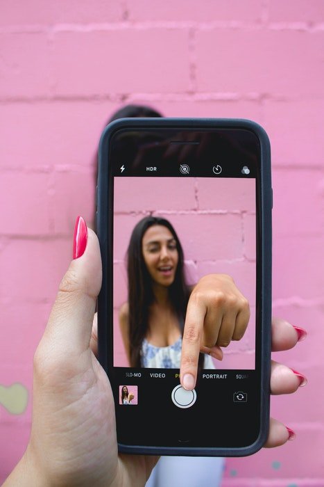 Cool photo of a girl on an iphone screen clicking the shutter herself
