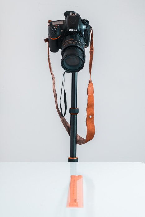 A DSLR camera on a tripod pointing down to a table