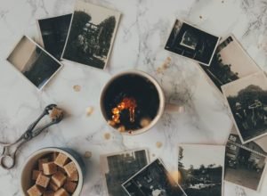 overhead photo of a coffee mug on a table with black and white polaroid photos