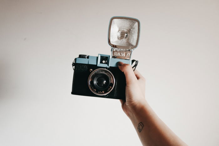 A person holding a vintage camera with an external flash