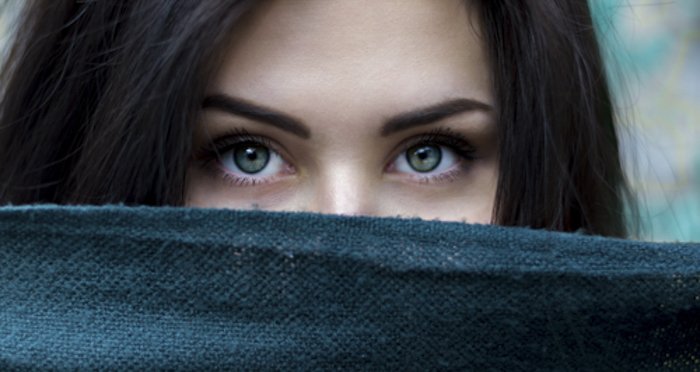 portrait photo of a girl with half of her face covered by a dark fabric