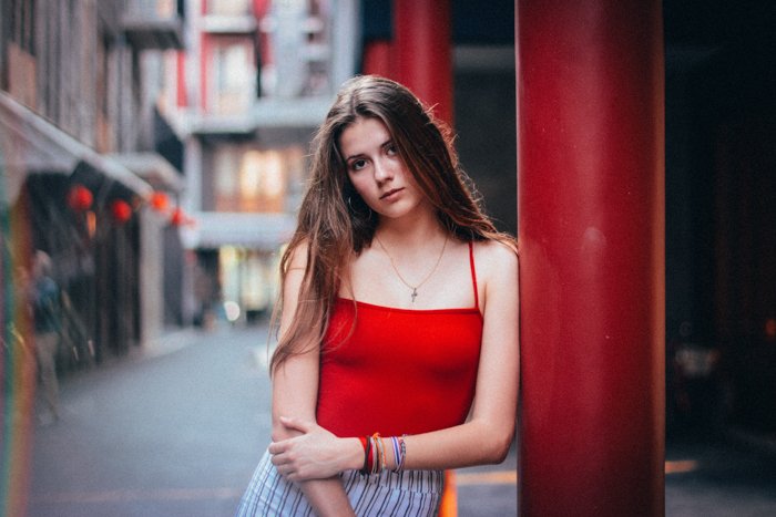 photo of a girl leaning at a red column