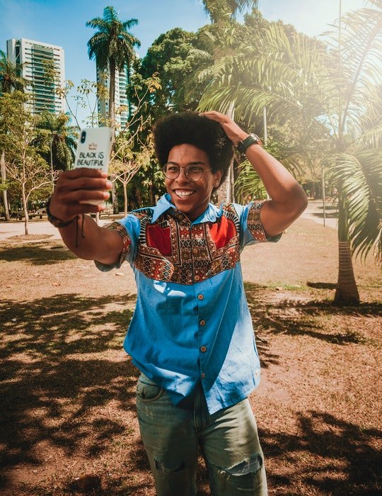 A young man posing for a selfie in front of tropical trees