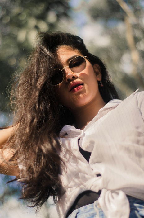 A girl lookng down posing in sunglasses